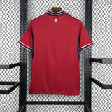 Red sports jersey with a logo on the chest, hanging against a black metal fence.