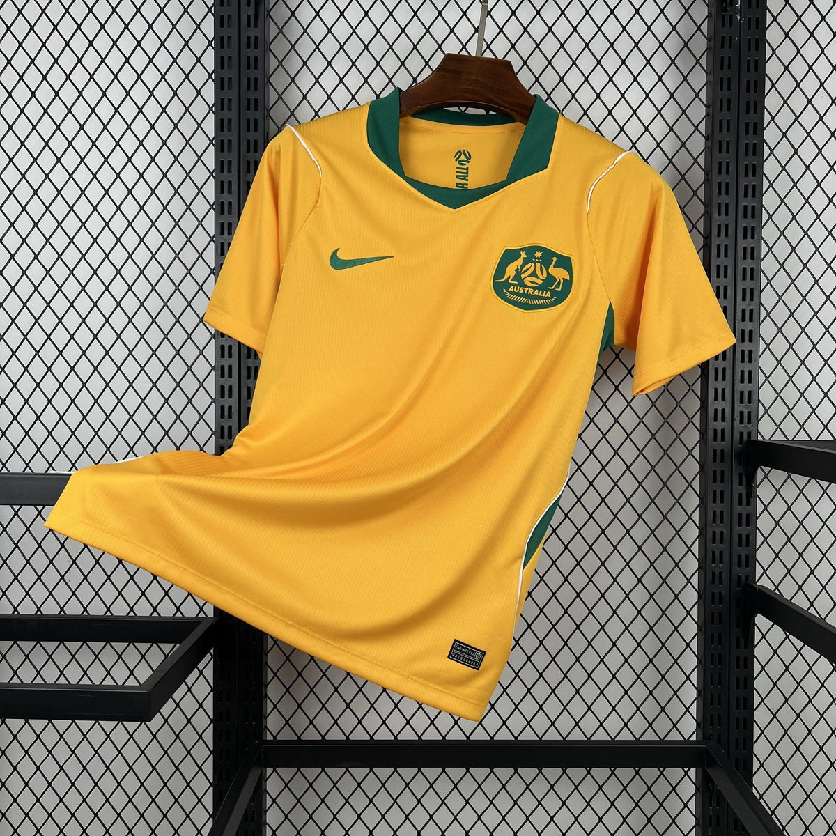 Yellow sports jersey with a logo on a hanger against a wire mesh background