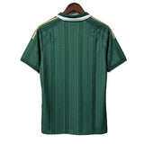 Green sports jersey with white and gold accents on a hanger against a gray background