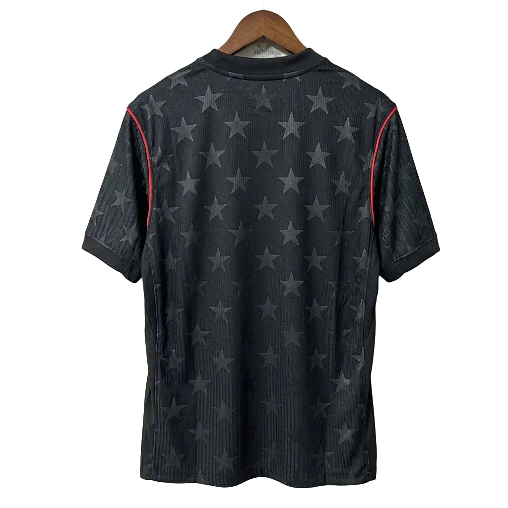 Black t-shirt with star pattern on a wooden hanger against a white wall