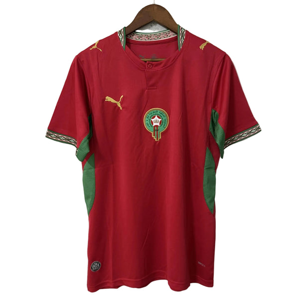 Red sports jersey with green accents and a logo on a hanger against a white background