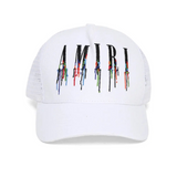 White cap with 'AMIRI' logo featuring colorful paint-like design on a white background