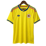 Yellow sports jersey with Adidas logo on a hanger against a gray background