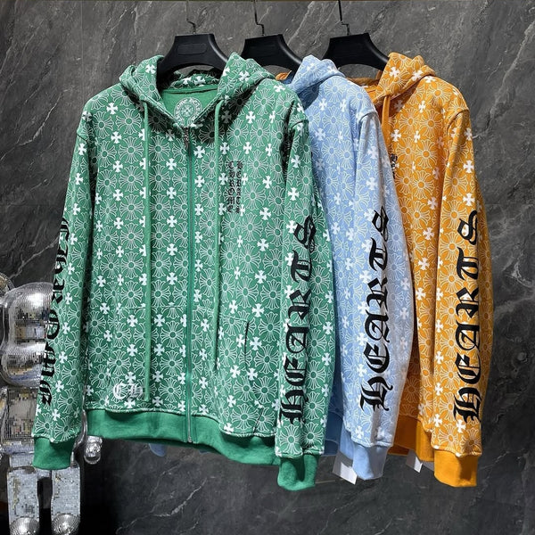 Three hoodies in green, blue, and orange hanging on a rack against a dark marble wall.